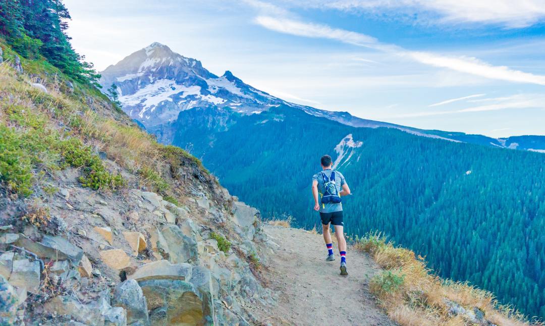 man runs along mountain trail path