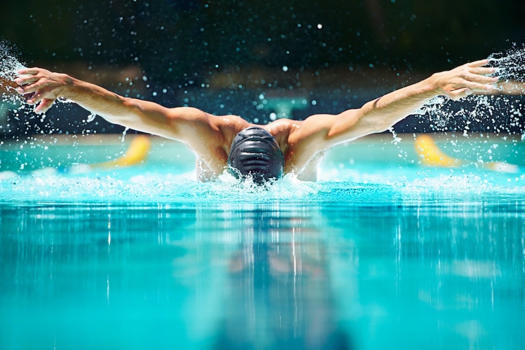 A male swimmer doing the butterfly stroke swimming toward the camera
