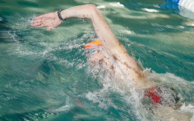 Male swimmer swimming in lane in pool with right arm out of water