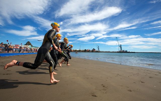 Pro female triathletes run into the water at the start of a race