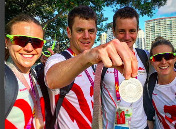 Jonny Brownlee holds silver medal up to camera as teammates Vicky Holland, Alistair Brownlee and Jess Learmonth smile for camera