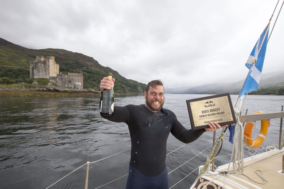 Ross Edgley holding an award and bottle of Champagne