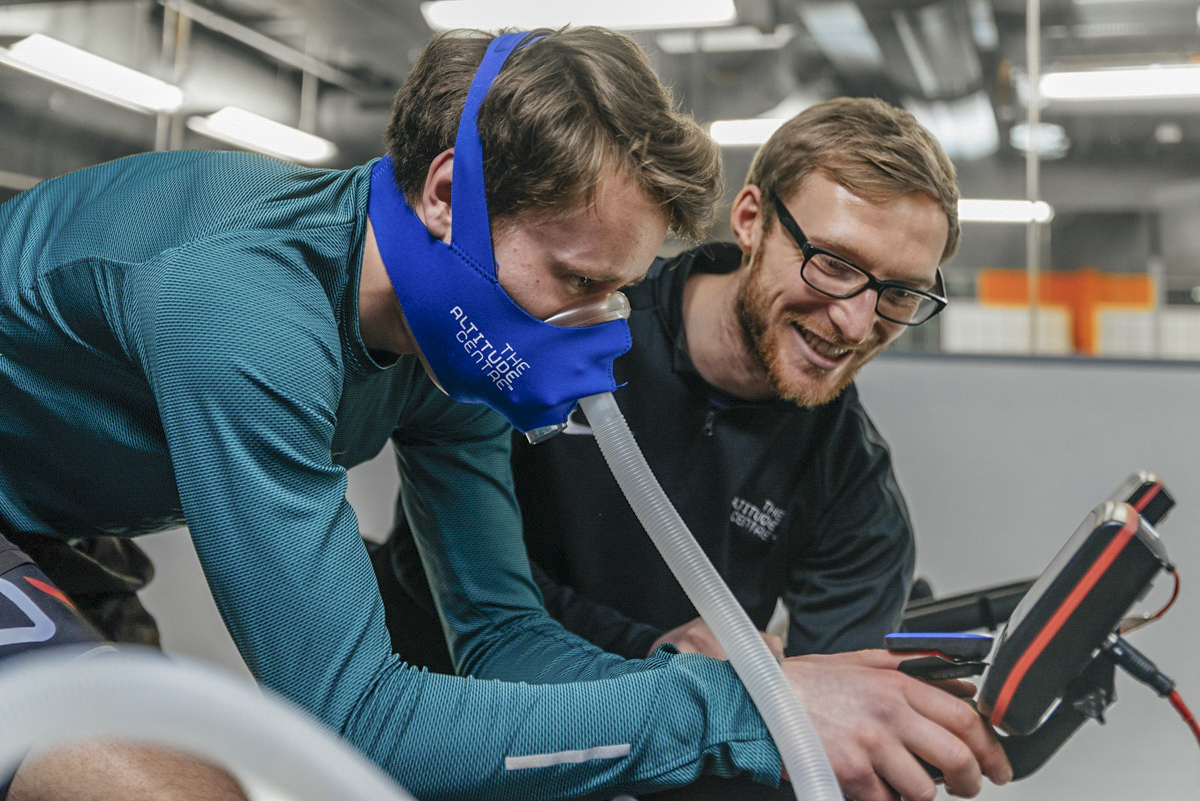 Man training on a bike at the Altitude Centre wearing a mask