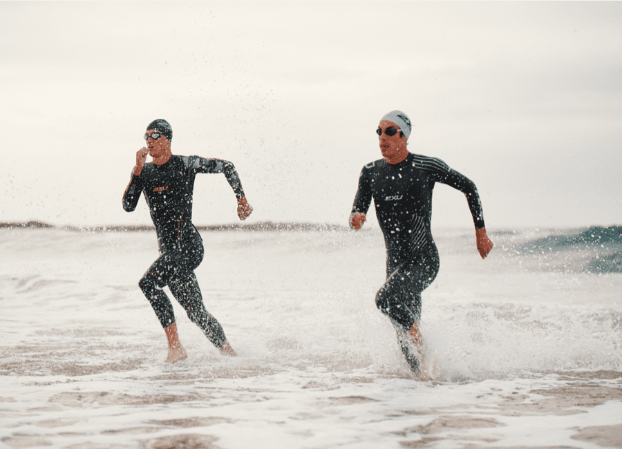 Two triathletes running to the shore
