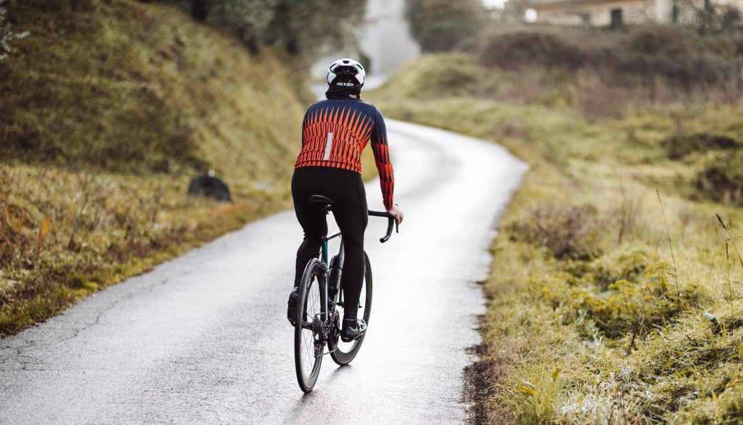 Person cycling on country road in bright jacket