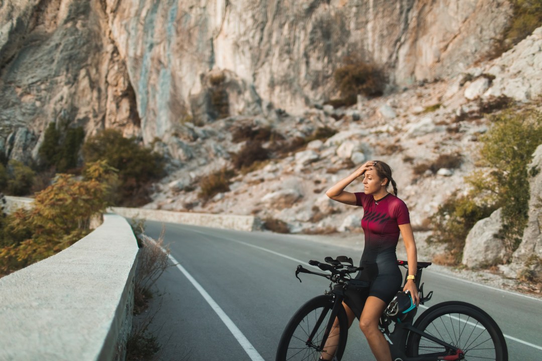 Female athlete looking tired mid-training ride on side of road
