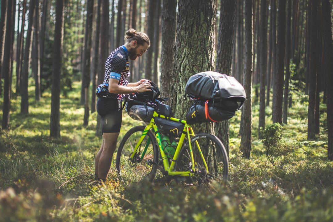 A man loading his bikepacking bags in the woods