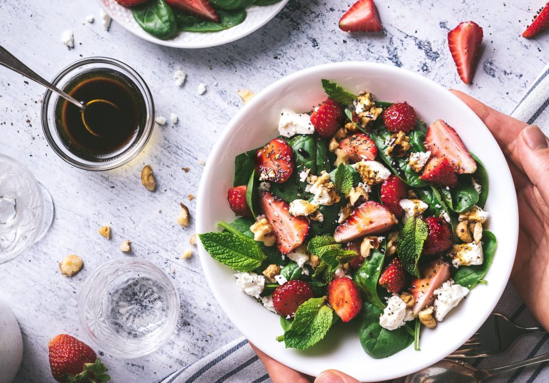 plate of keto salad with greens cheese, berries and nuts