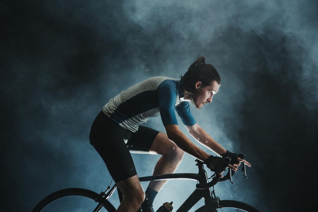 Man cycling against dark background