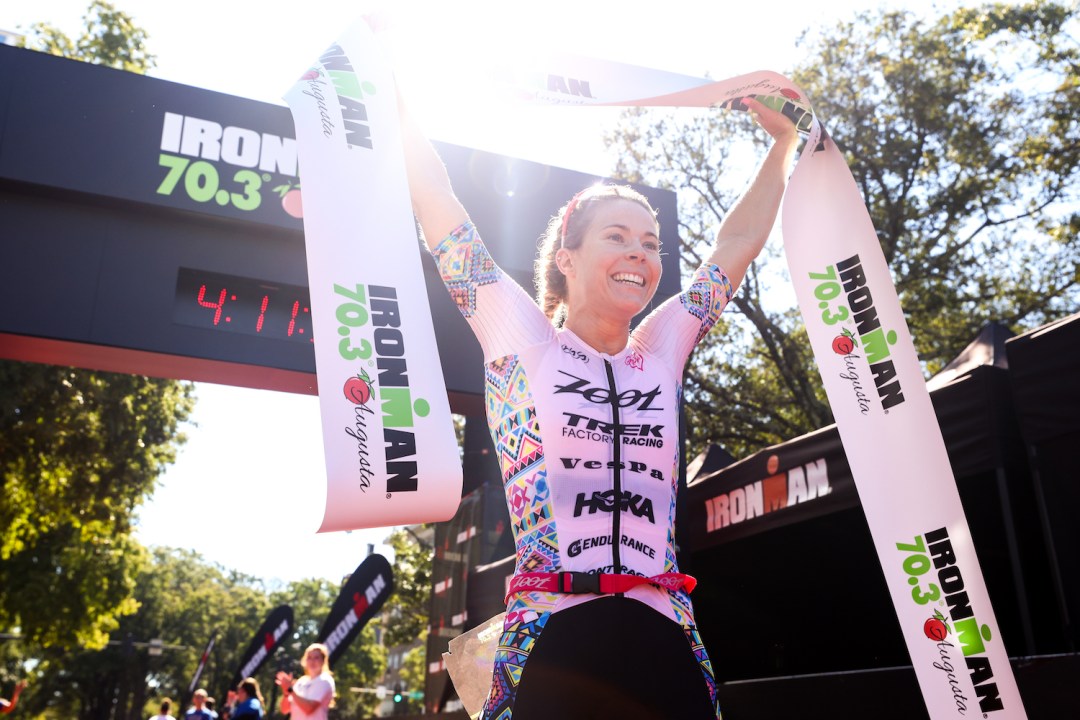 Ellie Salthouse holds the finish tape aloft after winning Ironman 70.3 Augusta