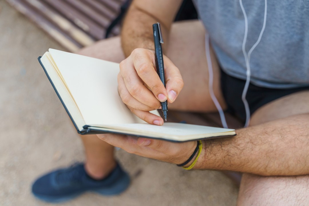 Man sitting in a park writing in a notebook - close up