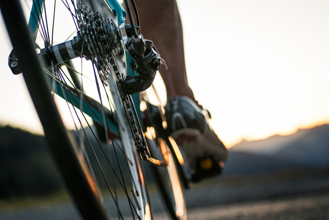 Close-up of a road cyclist riding towards sunset