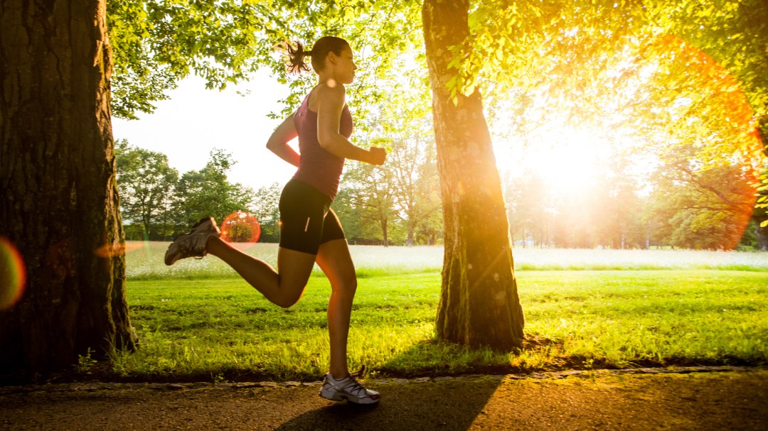 Young woman jogging in park at sunset.