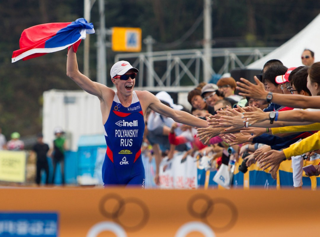 Dmitry Polyanskiy of Russia runs down the finish cute waving a Russian flag en route to winning the 2012 Tongyeong ITU Triathlon World Cup, in South Korea