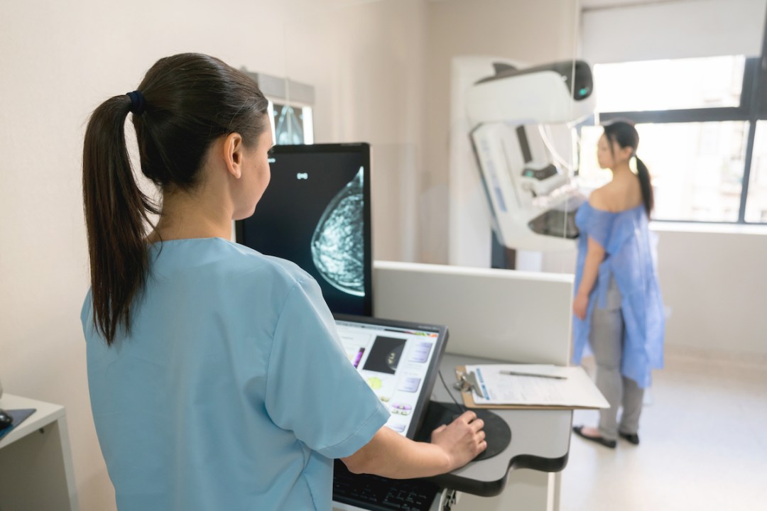 Unrecognisable nurse takes a mammogram exam on an adult female patient