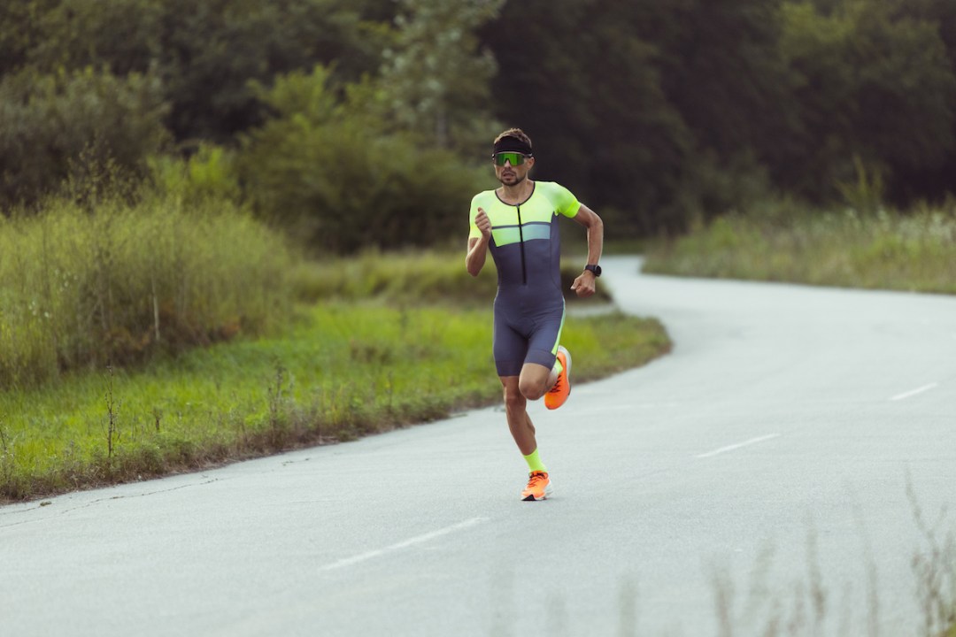 Young professional male triathlete running on open road