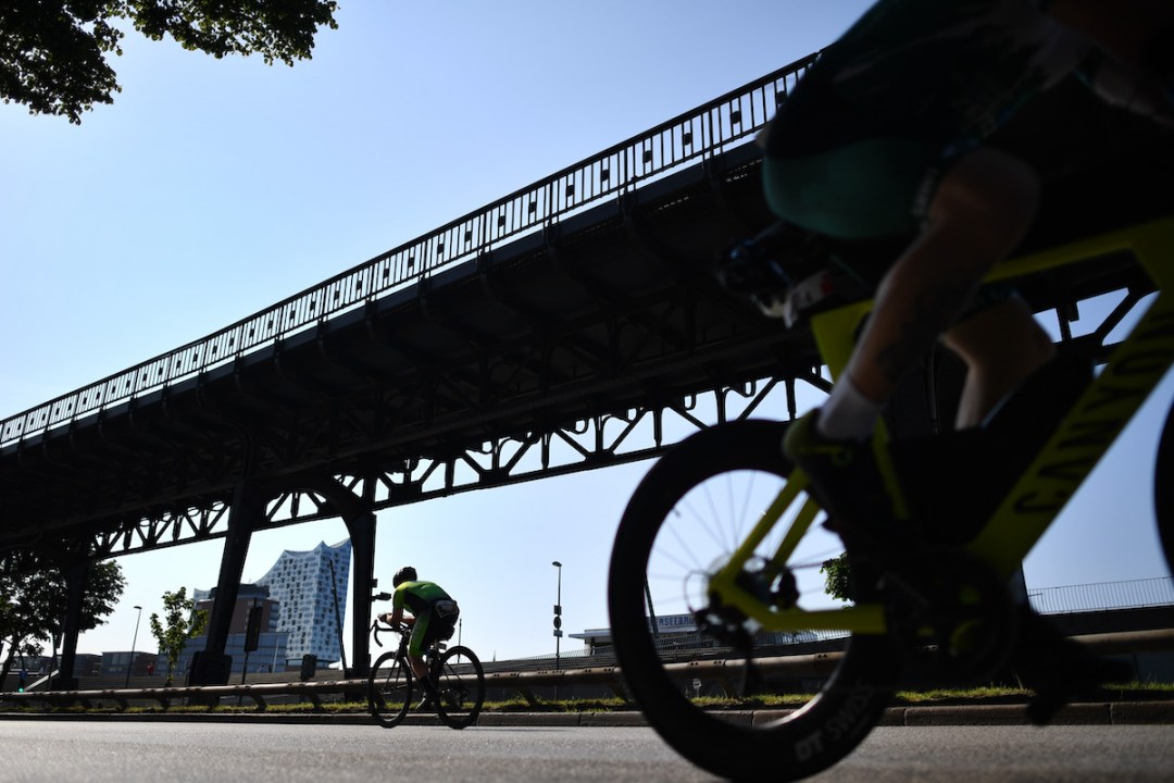 Silhouettes of two cyclists riding under a bridge on the Ironman European Championship bike course