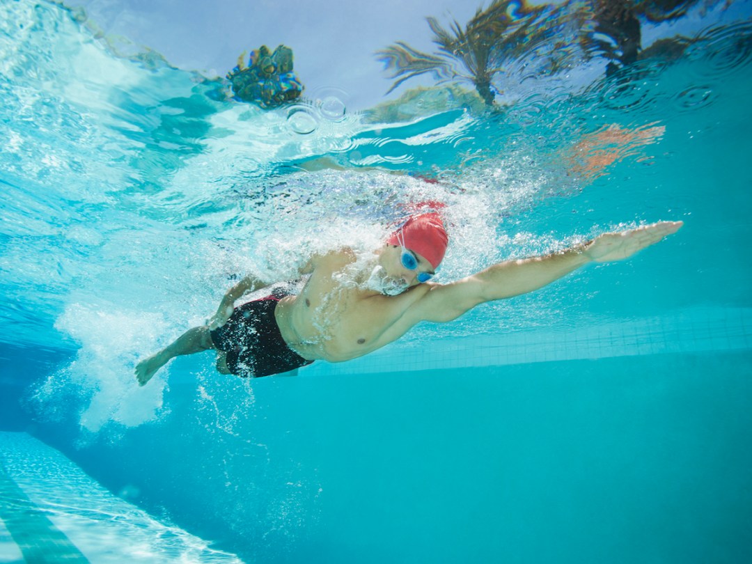 Male swimmer swimming in an outdoors swimming pool
