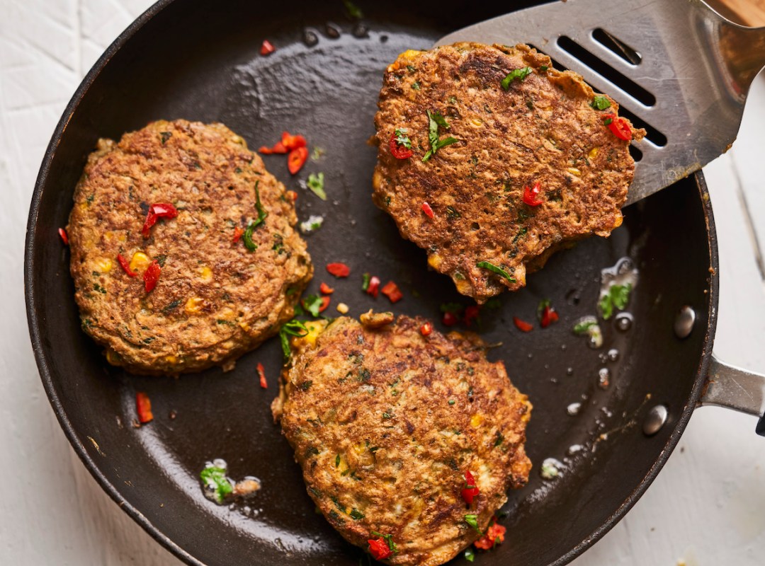 Three sweetcorn and sweet potato frittatas in a pan, one on top of a spatula