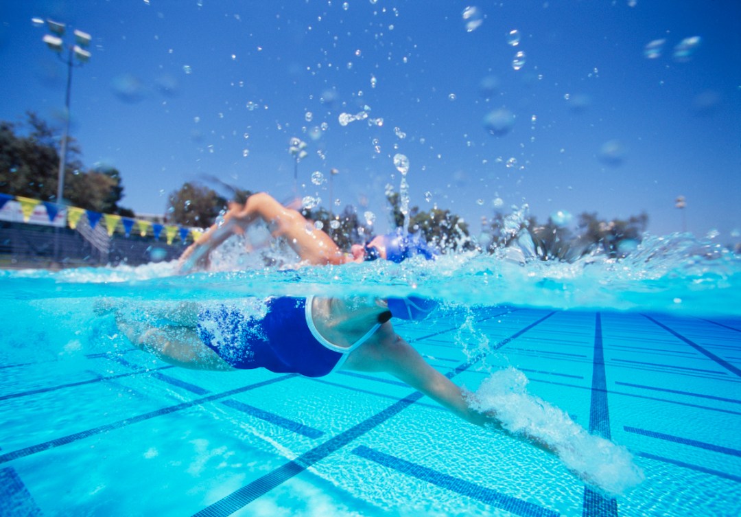 Female swimmer breathing to one side while swimming in an outdoor pool in the sunshine