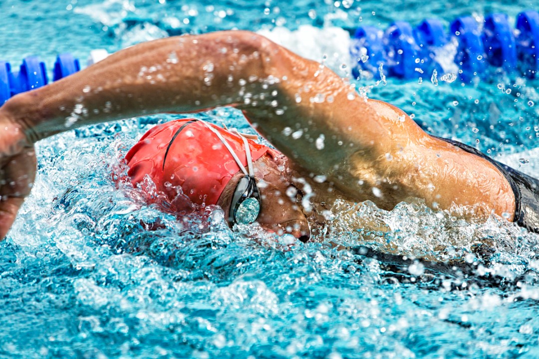 Male swimmer racing freestyle in the pool, breathing to the side