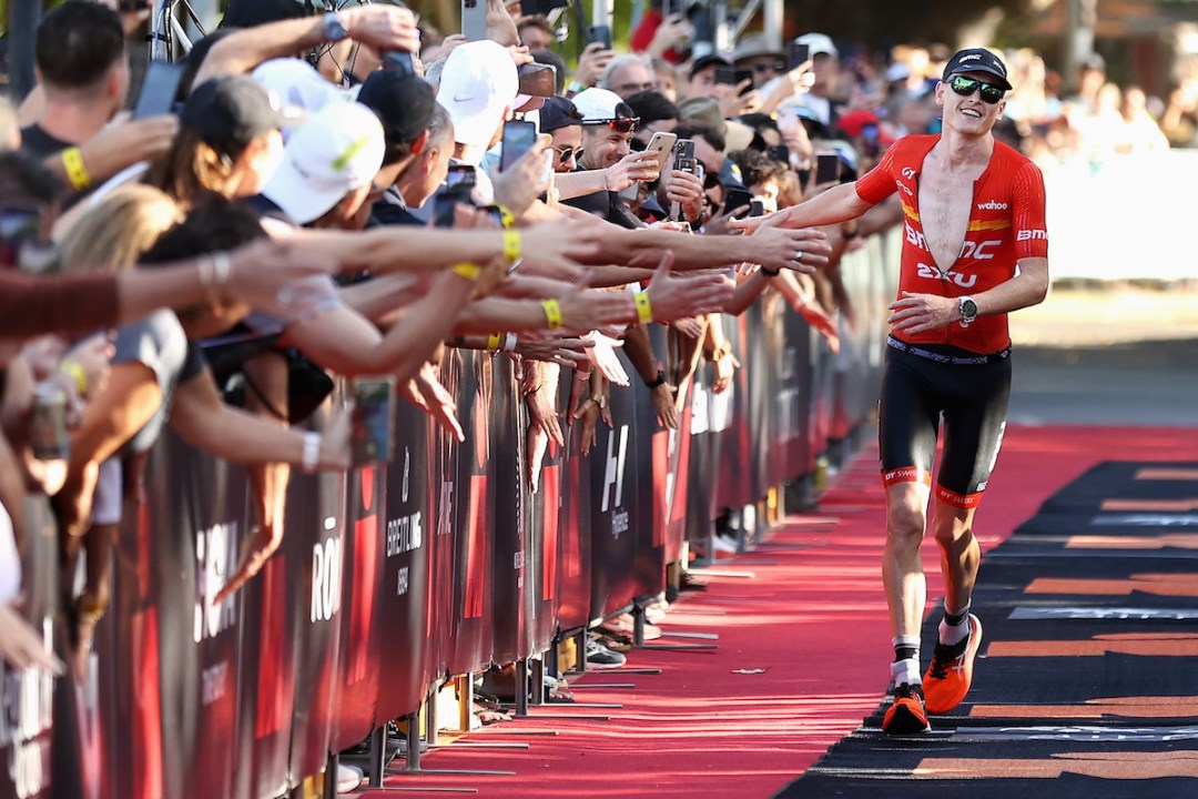 Australian triathlete Max Neumann celebrates with the crowd as he runs down the finish chute to win the 2022 Ironman Cairns, Australia