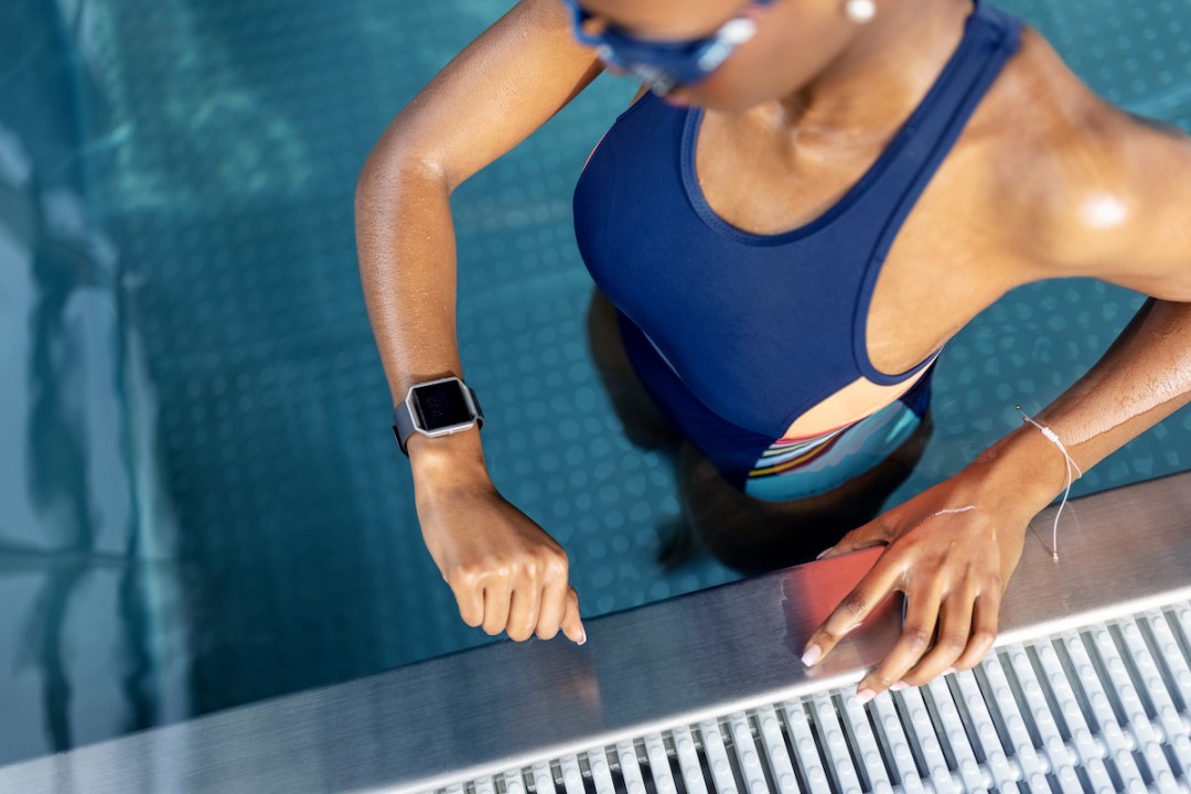 Top view of a woman in swimming pool checking her performance on smart watch