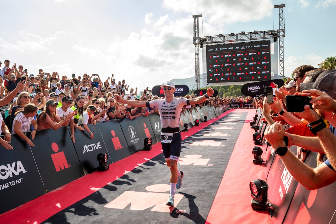 French triathlete Leon Chevalier runs down the red carpet flanked by fans, arms aloft, to win Ironman Mallorca 2021