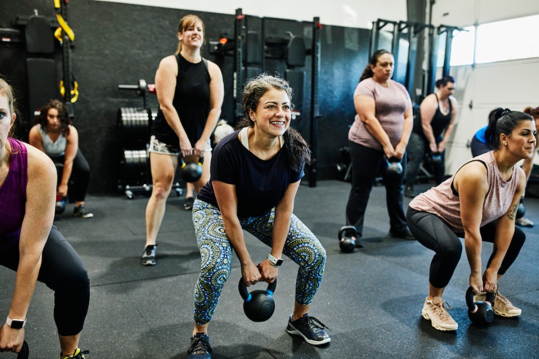 Group of women of various ages doing kettlebell swings during a gym class