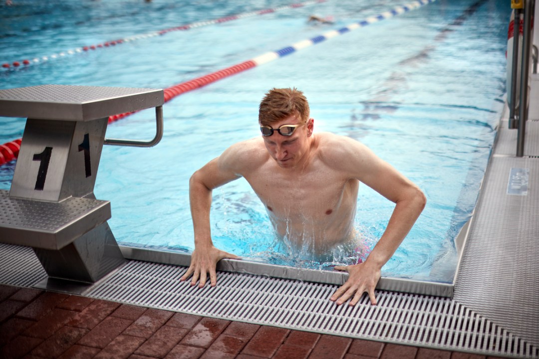 Male swimmer climbing out of pool