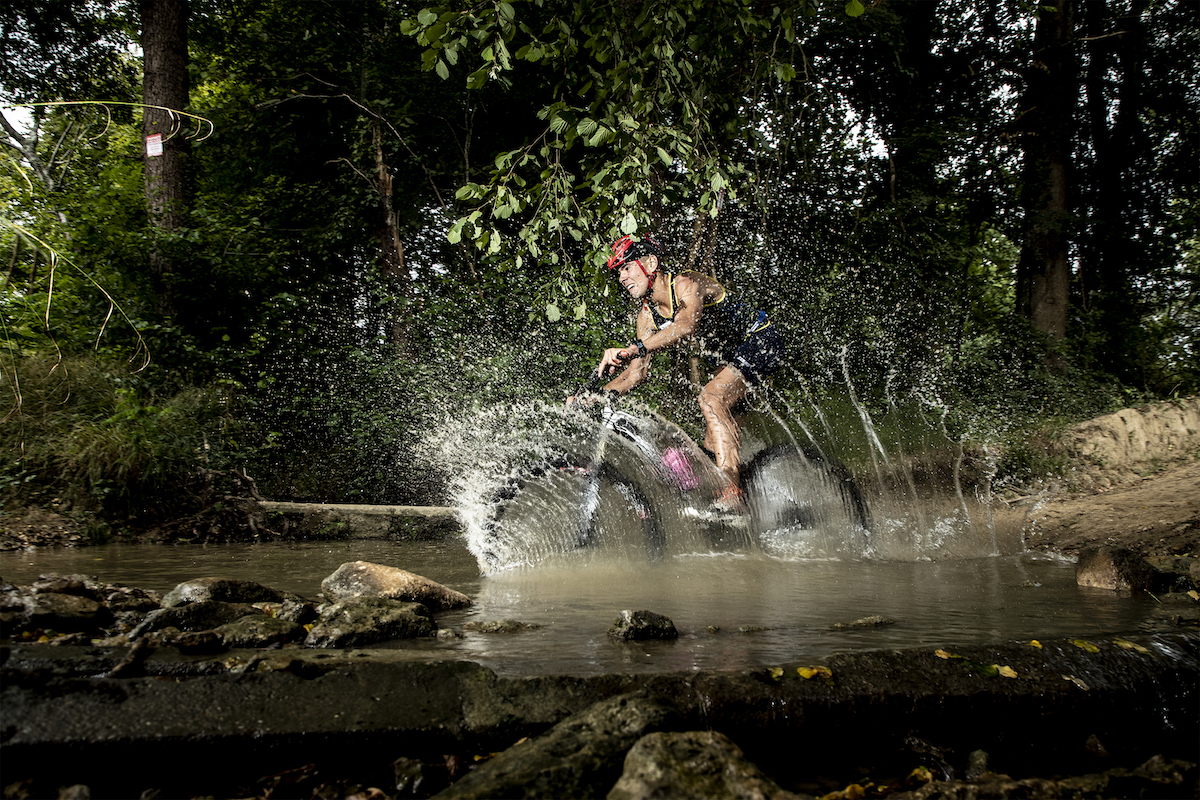 Male athlete cycling through water during an Xterra race