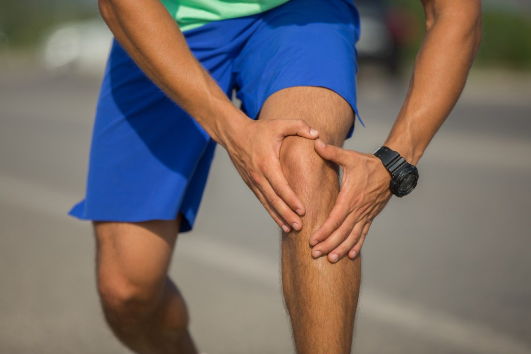 Male runner holding knee in pain
