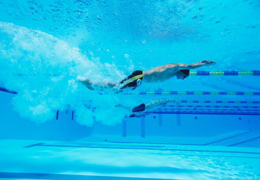 Underwater shot of three male athletes racing in swimming pool