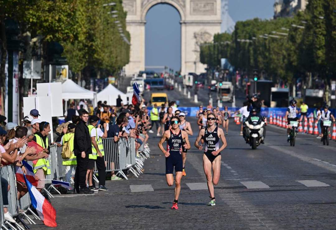 France's Cassandre Beaugrand (R) and England's Beth Potter (L) run with The Arc de Triomphe in the background during the Paris Test Event for triathlon, 2023