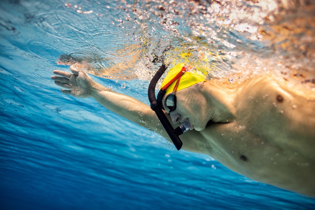 Underwater shot of young male swimmer practising front crawl in a swimming pool while using a snorkel