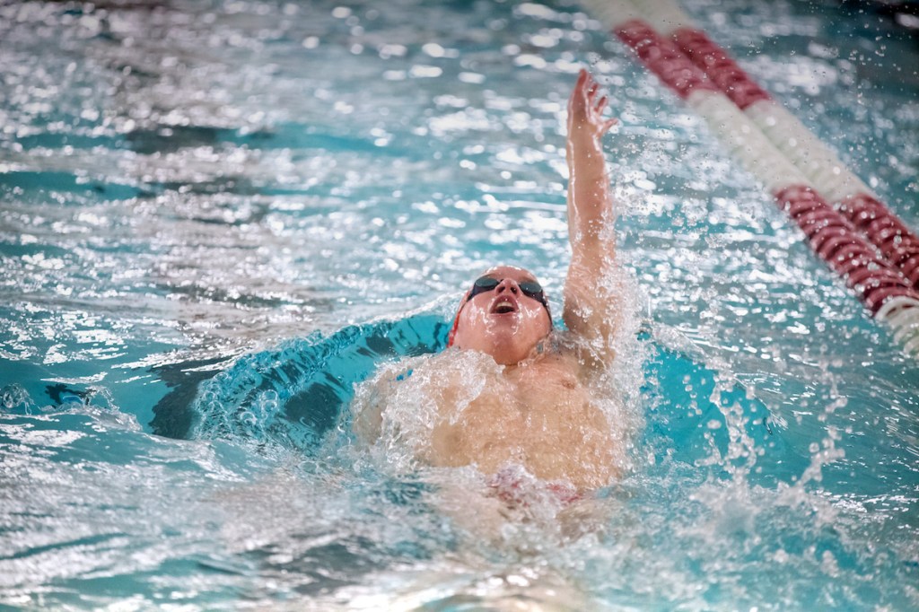 Young man swimming backstroke for boys varsity school sports