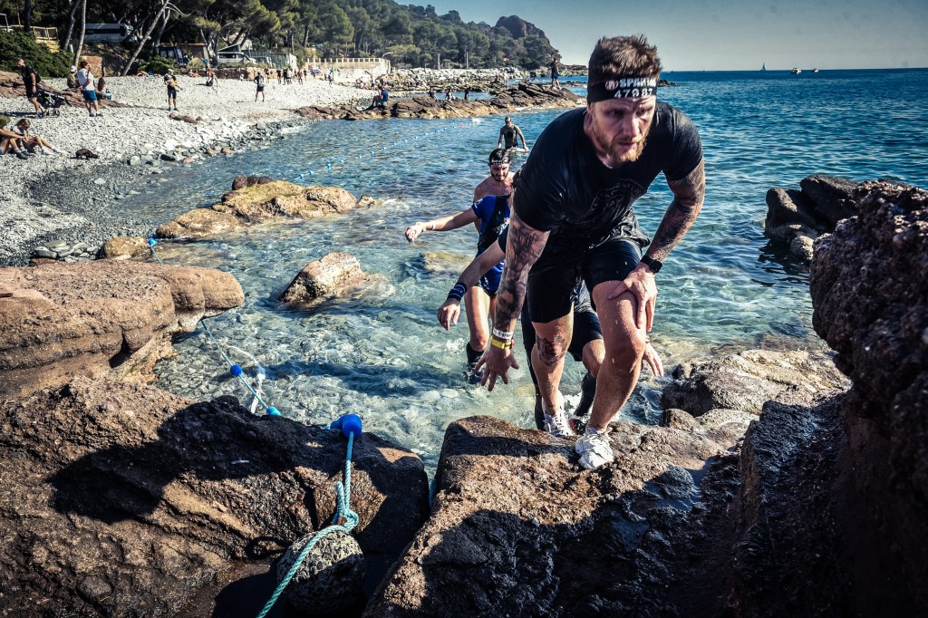 Male competitors climbing out of the sea during a race