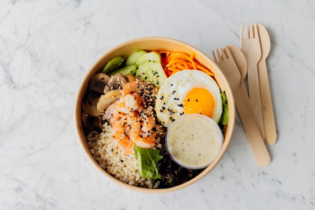 Healthy and nutritious lunch box. Takeaway food on marble background. Cardboard reusable box with healthy food. Directly above with copy space