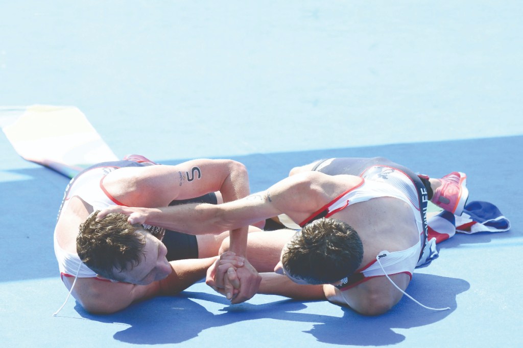 Alistair and Jonathan Brownlee embrace on the ground after the 2016 Rio Olympic triathlon