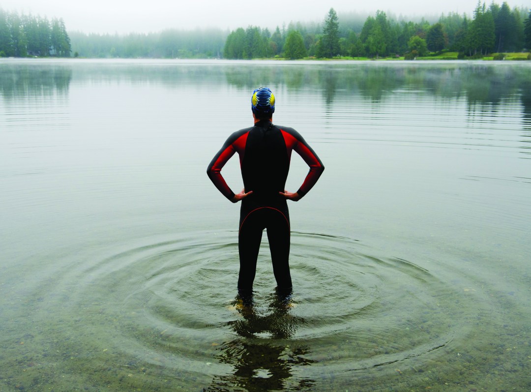 Man with hands on hips standing looking out across a lake