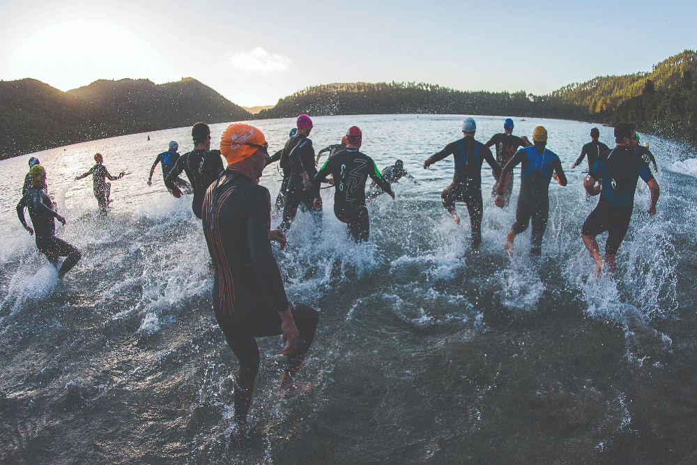 Swimmers entering water at start of triathlon