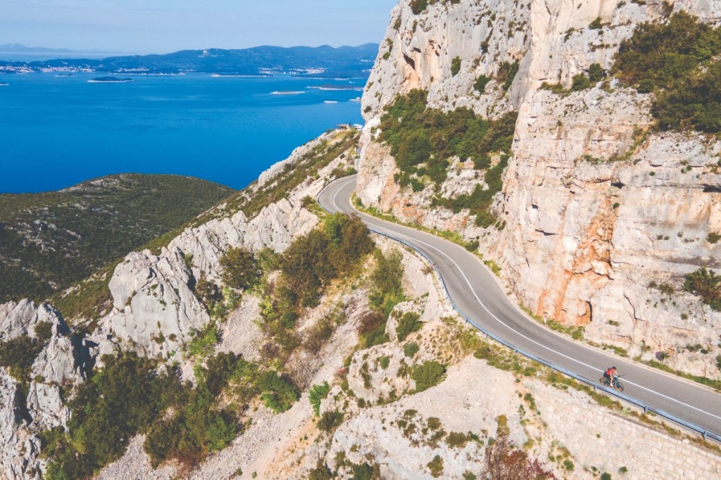 Cyclist on mountain road with sea backdrop