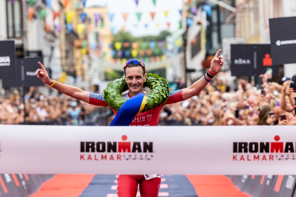 Alistair Brownlee crossing Ironman finish line wearing garland around neck