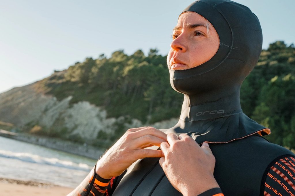 Female swimmer pulling on a neoprene swim balaclava