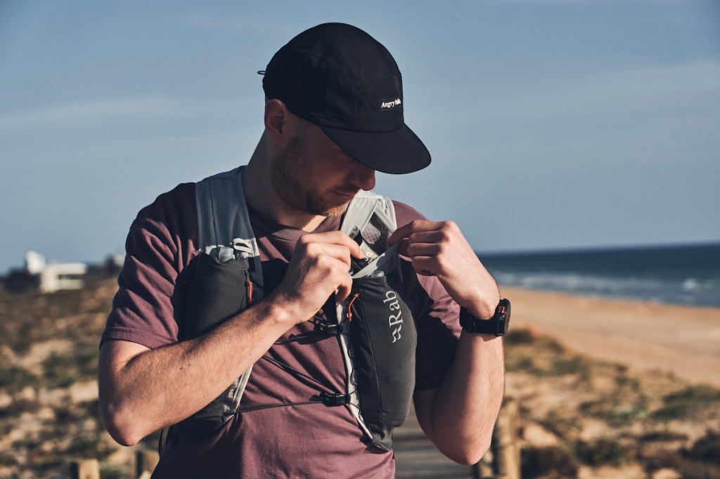 Man lifting energy bar out of run vest pocket