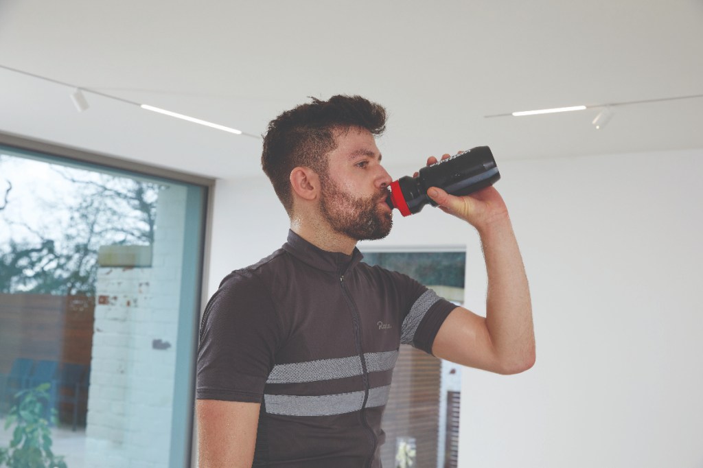 man drinking water while riding bike indoors