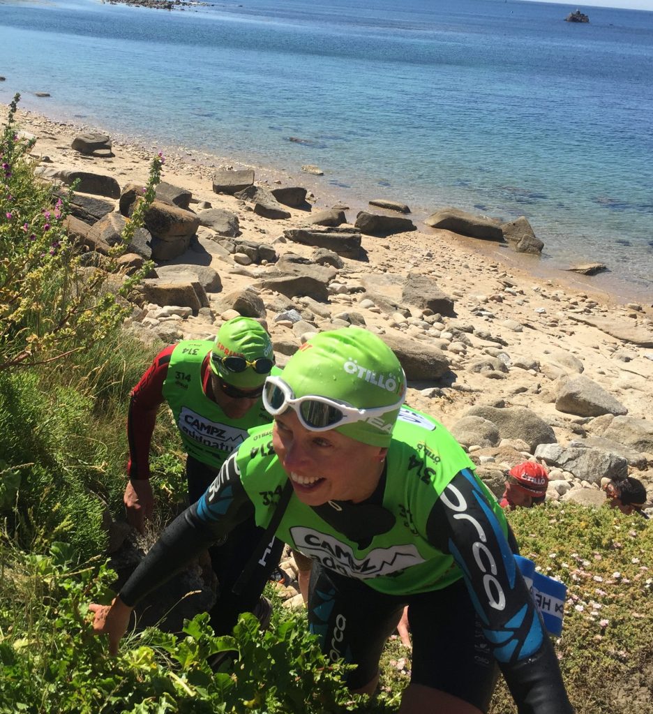 Female athlete climimbing rocks at an OtillO swimrun race