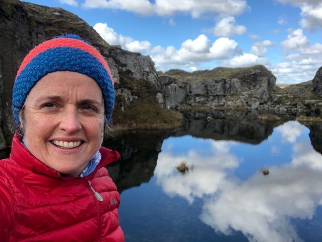 Photo of Jude Palmer standing by a lake in a bobble hat