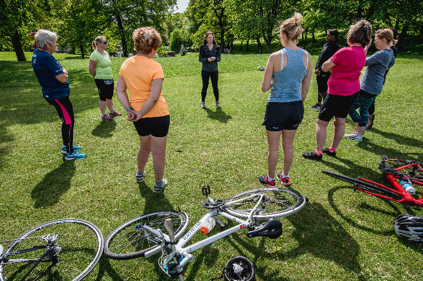 Group of women standing on grass next to their bikes