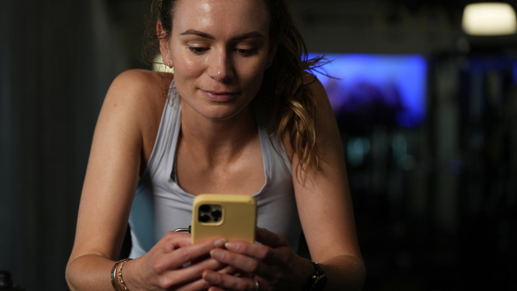 Female athlete in workout clothing looking at a mobile phone